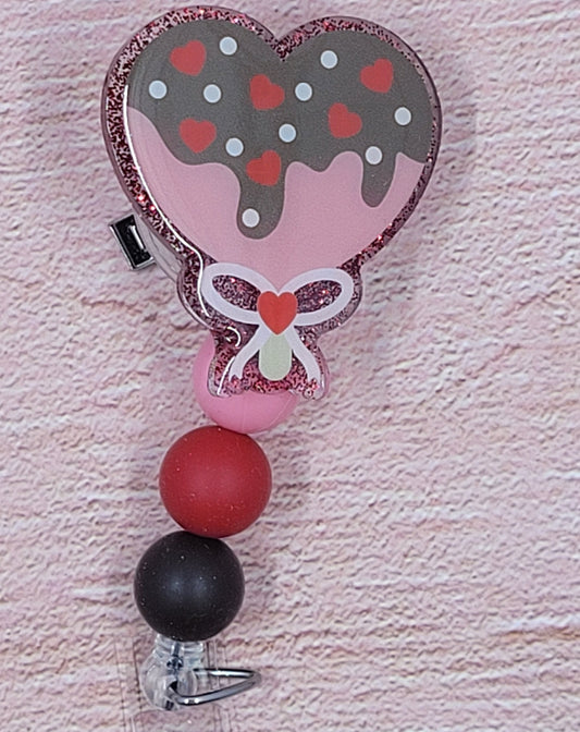 Chocolate covered strawberries....out....Chocolate covered heart.....in with sprinkles! New to our badge reel line this one will surely steal someone's heart. Featuring a red glitter base and coordinated beads, this is the perfect accessory for the holiday season.