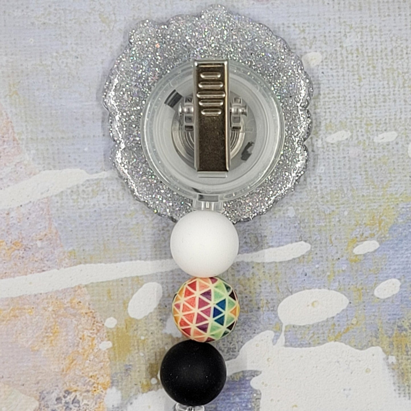 This badge reel, featuring the phrase "Accept Love Understand", aims to promote inclusivity across all backgrounds. It has a clear base with a glitter finish and is adorned with three coordinating silicone beads