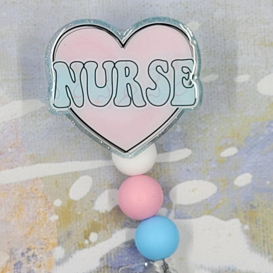 Introducing the new Nurse Badge Reel, part of our latest collection of Medical Badge Reels available now. Featuring Nurse in Blue lettering over a pink heart and a light blue glitter base adorned with coordinating beads, this Badge Reel is sure to catch the eye.