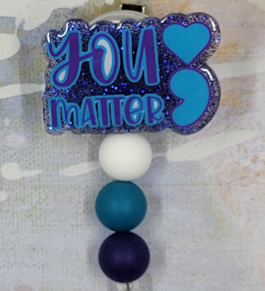 You Matter. You do and everything about you matters. This badge reel proudly promotes that statement. In blues and purples with a dark blue glitter base, this badge reel is a looker. 3 color coordinated silicone beads finish the look.