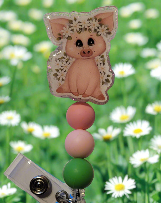 Unleash your inner whimsy with this delightful Badge Reel starring a charming little Floral Piggy, complete with flower-festooned head band and a sparkling pink backdrop. And don't forget the adorable trio of matching silicone beads for a dash of extra charm. Perfect for all animal enthusiasts!