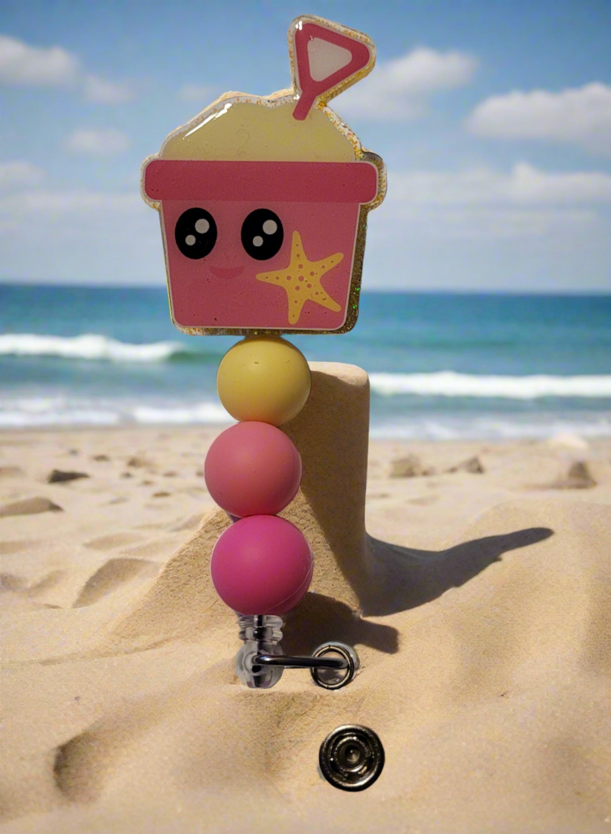 Heading to the beach? Grab your shovel &amp; pail for some sandy fun! With a cheerful pink pail adorned with a bright yellow star fish and color-coordinated silicone beads to top it off.