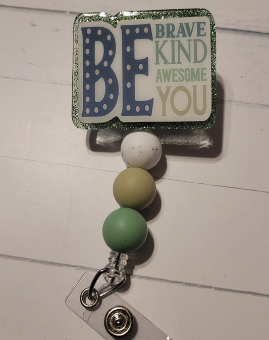 This badge reel promotes self-expression with the message "Be You." The bold lettering in various shades of green pops against a glittery green background. It also features three coordinating silicone beads for added flair.