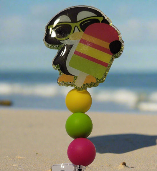 Unlock the ultimate summer vibes with this Badge Reel we call Penguin Pop. This stylish acrylic badge reel features a cool penguin wearing sunglasses enjoying a popsicle and adorned with vibrant silicone beads, giving it a classic and lively look.