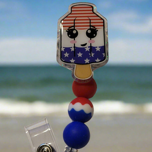 Beat the heat of summer with the time-honored treat of the Bomb Pop popsicle. This acrylic badge reel features red, white, and blue silicone accent beads to complete its classic look.