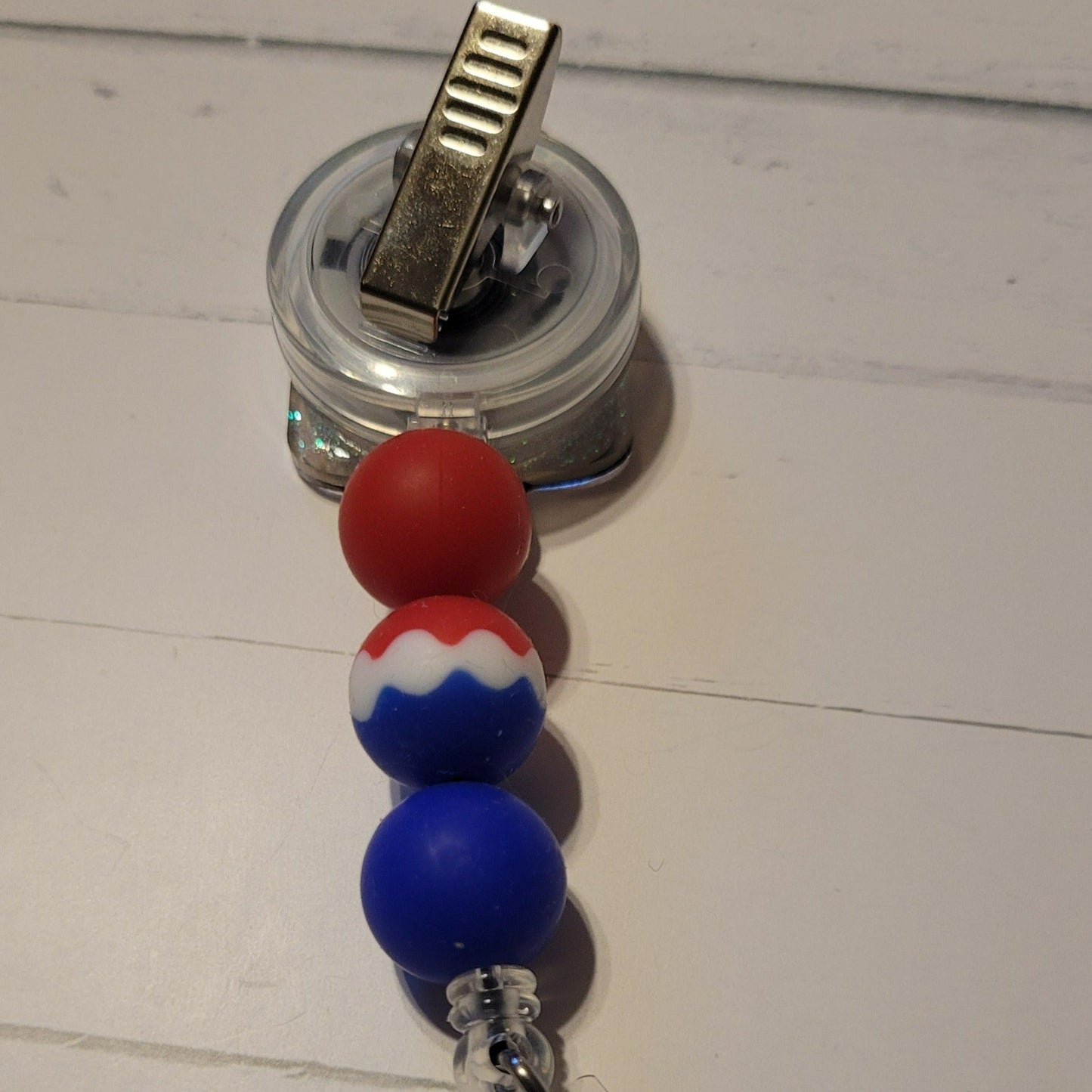 Beat the heat of summer with the time-honored treat of the Bomb Pop popsicle. This acrylic badge reel features red, white, and blue silicone accent beads to complete its classic look.