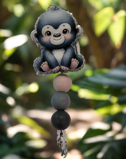 Looking for a charming badge reel? Well, look no further because we've got our Baby Gorilla here! With a glittery gray back and 3 matching silicone beads, it's perfect for all the animal lovers out there.