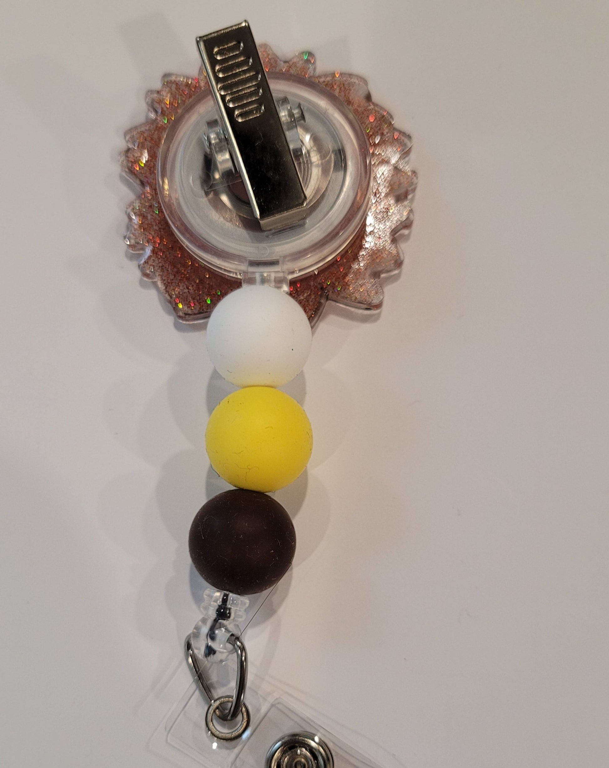Dare to stand out with the fierce Sunflower Leopard Print Badge Reel. Its vibrant colors and dazzling glitter base will make a statement, enhanced by three coordinating silicone beads for a touch of adventure.