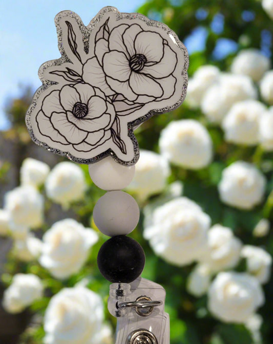 A white rose carries many meanings. In love it represents eternal Love. It can also represent fresh starts, unity and convey sympathy. The acrylic badge reel has a gray glitter back with 3 silicone color coordinated beads.