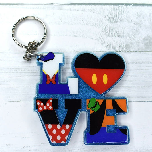 This stylish acrylic keychain flaunts a blue glitter base with mouse and friends in vinyl lettering - a perfect way to celebrate love!