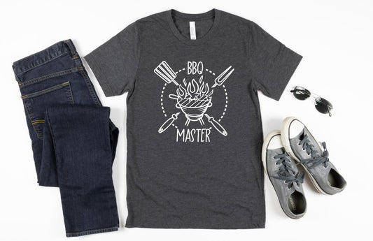 Fire up that smoker or grill and have your BBQ Master prepare you a backyard meal while styling in this shirt. In black or navy blue with a white image of a grill and utensils at the ready, crank up the heat!