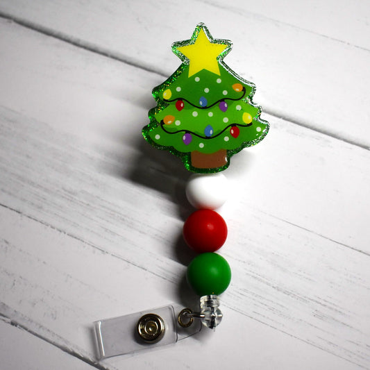 Tis the season for the lighting of the Christmas Tree. This badge reel makes a festive addition to your look with a green glitter background and white green and red silicone accent beads. Ideal for celebrating the Christmas Holidays.  