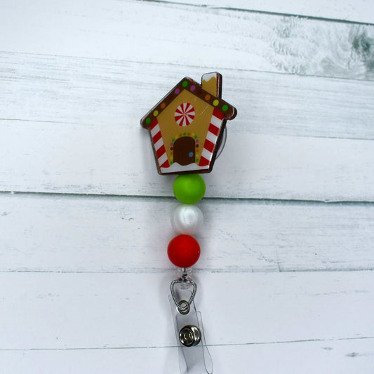 This acrylic Gingerbread House badge reel makes a festive addition to your look with green pearl and red silicone accents, ideal for celebrating the Christmas Holidays.