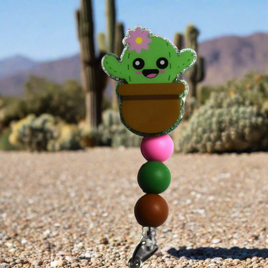 Cute and prickly all in this cute cactus in a pot badge reel. This little guy overlays a green glitter background. Finished off with 3 silicone color coordinated beads. Great for the plant enthusiast.