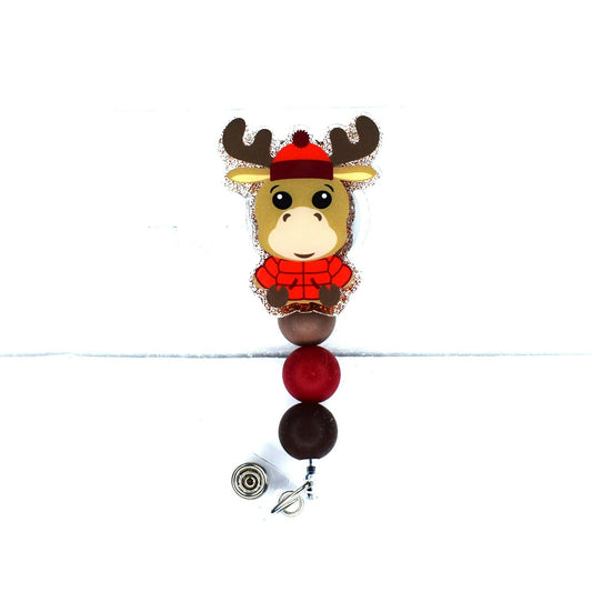 Introducing the Badge Reel Parka Moose! Showcasing a red puffy parka and a cozy knit cap, this charming moose is sure to bring a smile to your face. This stylish badge reel is finished with a red glitter base and three carefully chosen silicone beads.