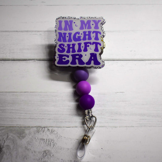This badge reel speaks of the hard work and dedication to chasing a dream, especially when that dream requires working nights. The design element features a purple glitter background with lettering in a light to dark purple palette accented by three purple silicone beads. In My Night Shift Era indeed.