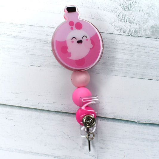 This spooky Pink Ghost Potion acrylic badge reel could be the mixture you need for a night of fright. 3 separate tones of pink  silicone accent beads add to this recipe.
