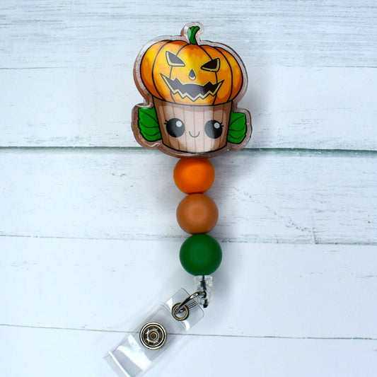 Here we have a scary cupcake Jack-o-Lantern acrylic badge reel featuring orange light salmon & green silicone beads. 