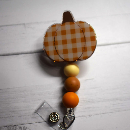 Pumpkins in plaid. Yes plaid. 2 different color combinations too choose from here. Tan glitter background, tan plaid and 3 silicone matching beads.
