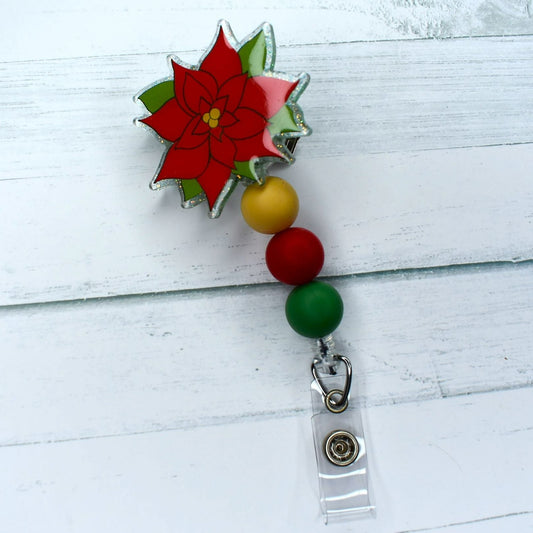 Make a statement this holiday season with the Poinsettia acrylic badge reel, adorned with red and green silicone beads for a festive finish.