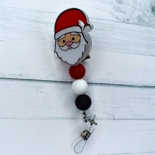 This Santa badge reel features an acrylic design, with white, black, and red silicone beads. An ideal stocking stuffer, it will bring festive cheer to the wearer.