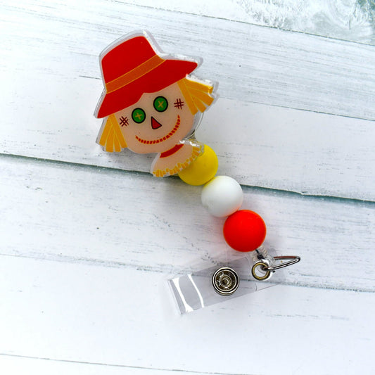 This cheerful scarecrow acrylic badge reel stands tall, protecting fields from bothersome crows. The yellow, white, and orange silicone beads complete its look.