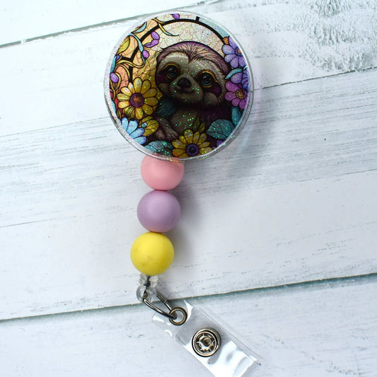 This acrylic badge reel showcases a vibrant sloth-on-stained-glass motif, with two separate choices of silicone beads for distinctive visual appeal