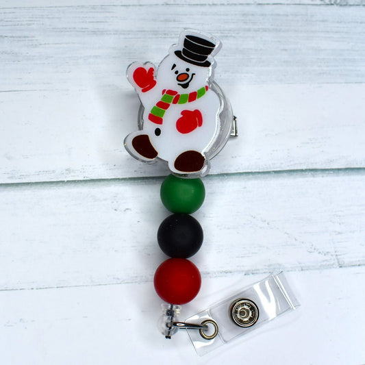This acrylic-constructed badge reel, designed in homage to the winter classic Frosty the Snowman, boasts festive red, black, and green silicone beads to spread holiday cheer.