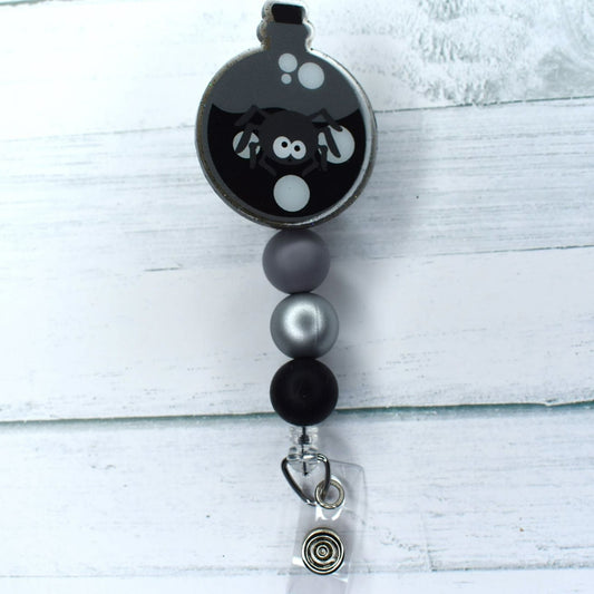 Unlock the mystical potential of the Halloween Spider Potion badge reel. Crafted of acrylic, this badge reel features a menacing arachnid atop a flask of mysterious potion, the perfect pairing of black, silver, and grey tones.