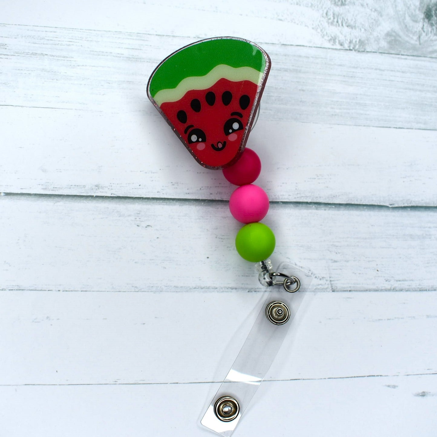 Experience the summer season with this slice of watermelon acrylic badge reel, highlighting pink, red, and green silicone accent beads.