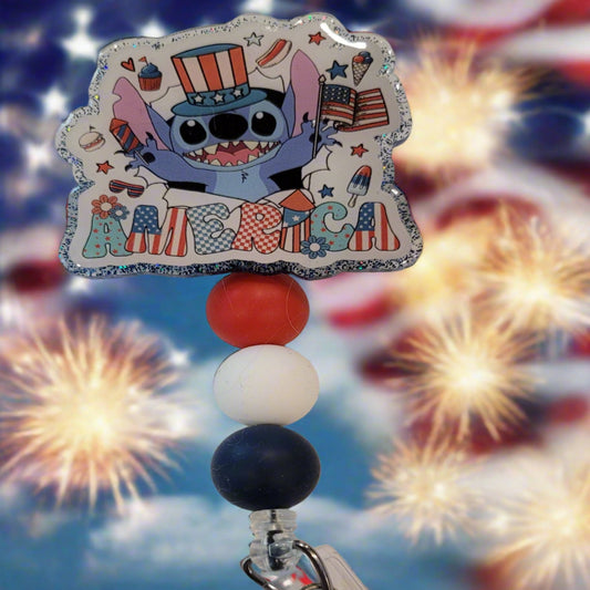 Experience America like never before with the Badge Reel America Alien Style! Embrace the summer spirit with cookouts, fireworks, ice cream, and everyone's favorite little blue alien. A dazzling blue glitter backing and 3 color-coordinated silicone beads add the perfect finishing touch to this out-of-this-world badge reel.