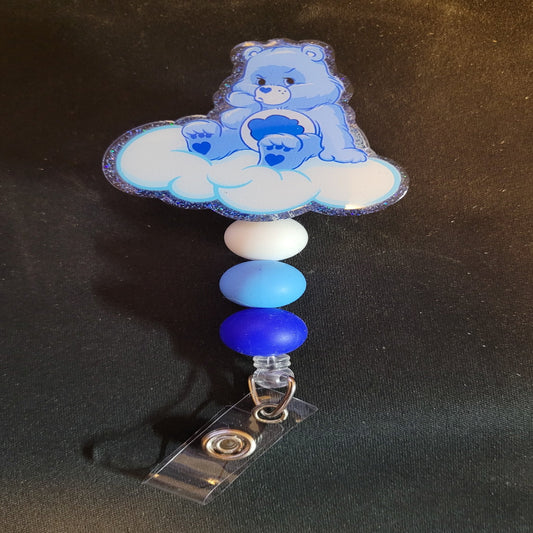 Looking for a charming badge reel? Well, look no further because we've got our Grumpy Bear Cloud is here! With a glittery blue back and 3 matching silicone beads, it's perfect for all the bear lovers out there.