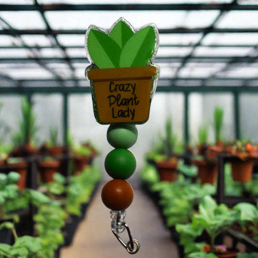 Yes they exist...Crazy Plant Ladies and we have the reel badge to prove it. A potted plated with the phrase Crazy Plant Lady overlays a green glitter background. Finished off with 3 silicone color coordinated beads. Great for the plant enthusiast.