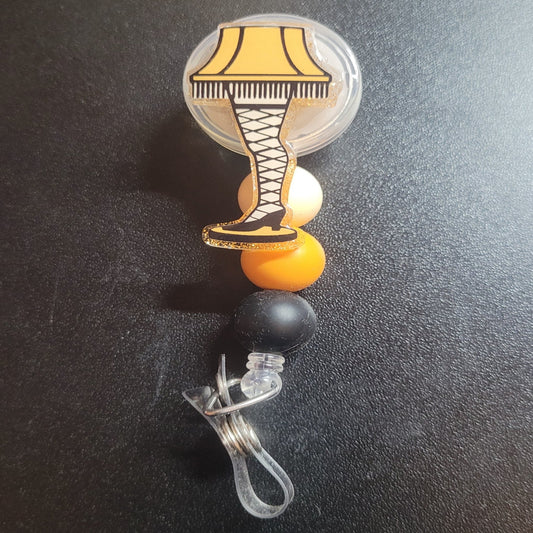 Be prepared for a double take when you wear our badge reel with the iconic Leg Lamp from A Christmas Story. With three coordinating silicone beads and a bright yellow glitter back, it's a festive accessory that's sure to catch eyes.