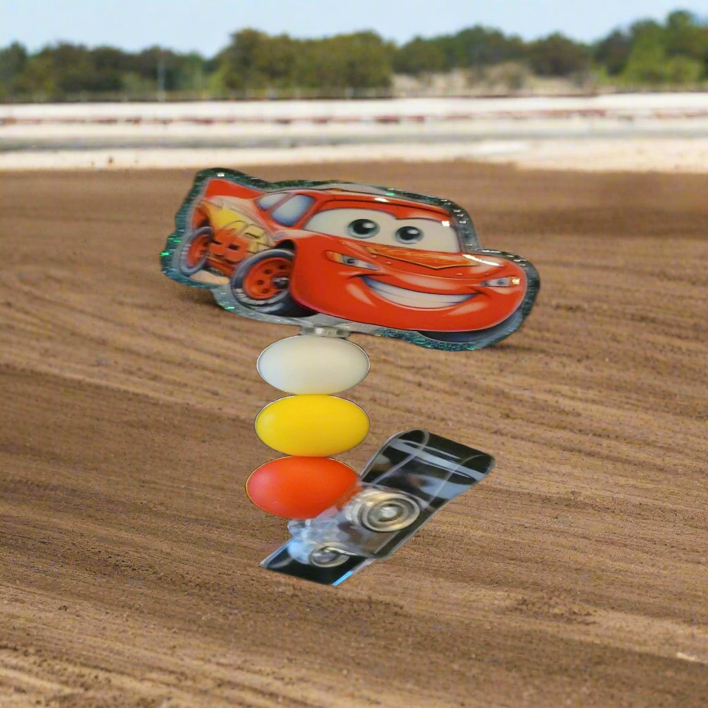 Lightning McQueen at you service. Racing hard on this acrylic badge reel. A shiny glitter base and is finished with 3 color coordinated silicone beads.