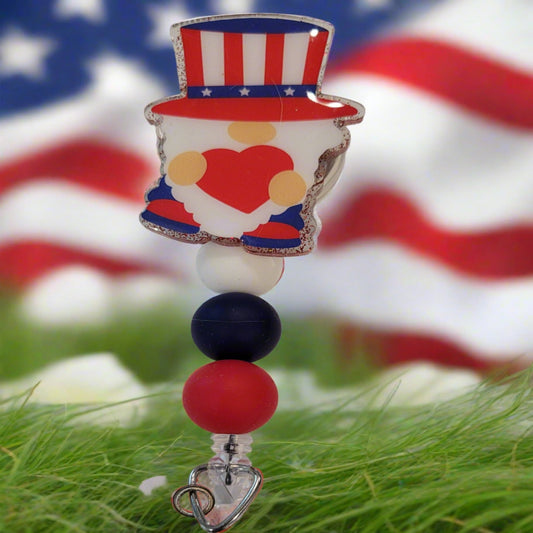 This playful badge reel features an adorable Patriotic Gnome channeling Uncle Sam, complete with a heart in hand. The design is topped off with a sparkly red backing and patriotic red, white, and blue silicone beads.