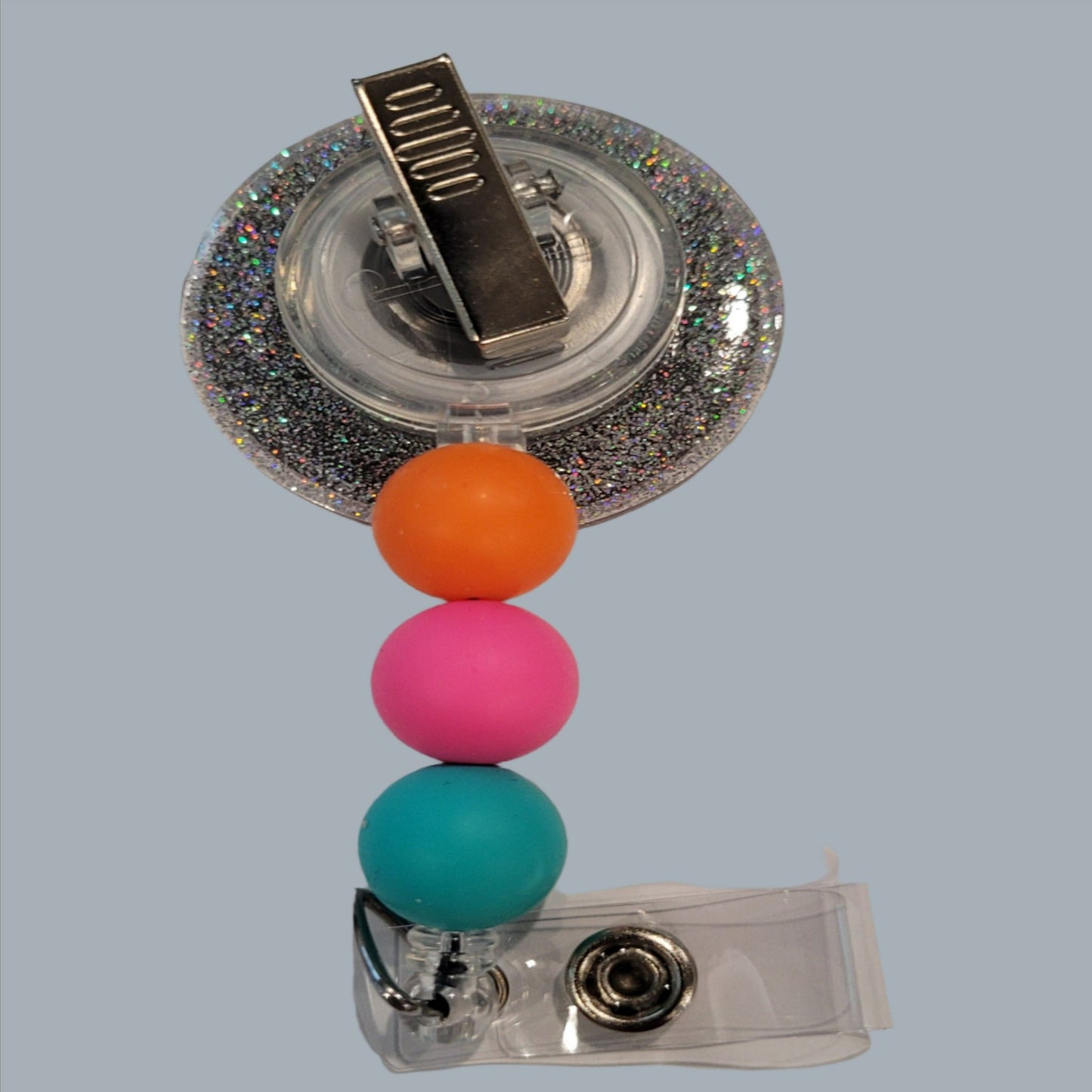 This acrylic badge features a unique, abstract design inspired by a deserted tropical island. It showcases a full range of vibrant, rainbow-like colors and is accented with a glitter back and three silicone beads in coordinating hues. It's sure to catch the eye.