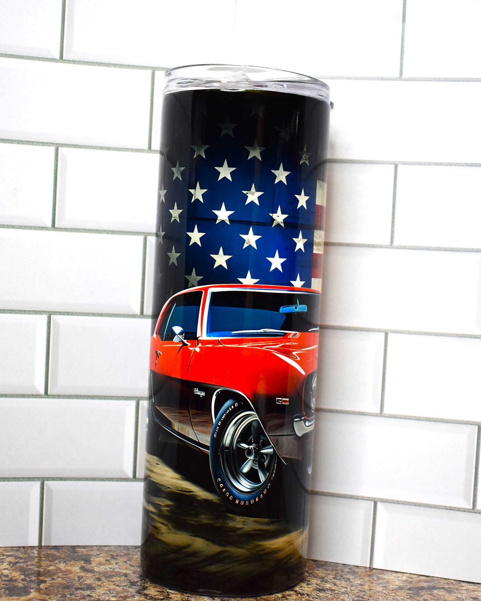 Muscle cars ruled the roads and this tumbler pays homage to the Chevy Camaro in classic red and the 2 black stripes down the hood with the American Flag in the background.