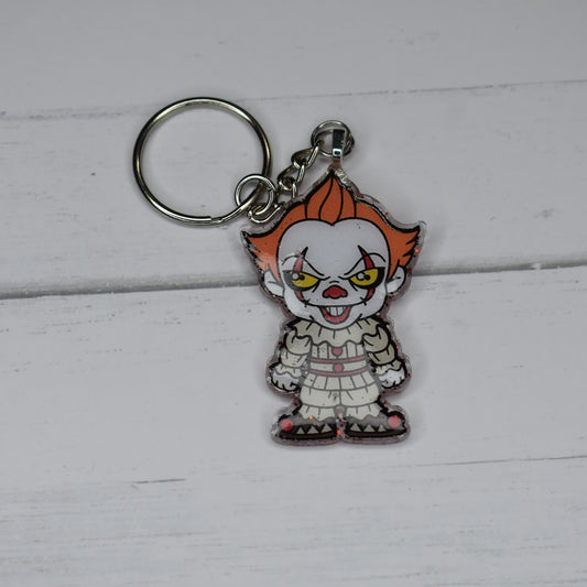 From our Horror Collection we give you the one and only Pennywise. Hand Crafted with durable acrylic resin, this mini Keychain Serial Killer comes with a blood red glitter back ground and full on image of Pennywise on the front. Watch the storm drains or you may end up floating like the rest.&nbsp;