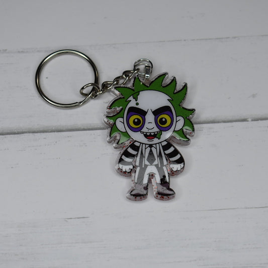 From our Horror Collection and I am only saying it once....Beetlejuice. Hand crafted with durable acrylic resin, this Keychain will stand up to even the meanest sandworm! Blood red glitter back and our green haired blast from the dead on the front.