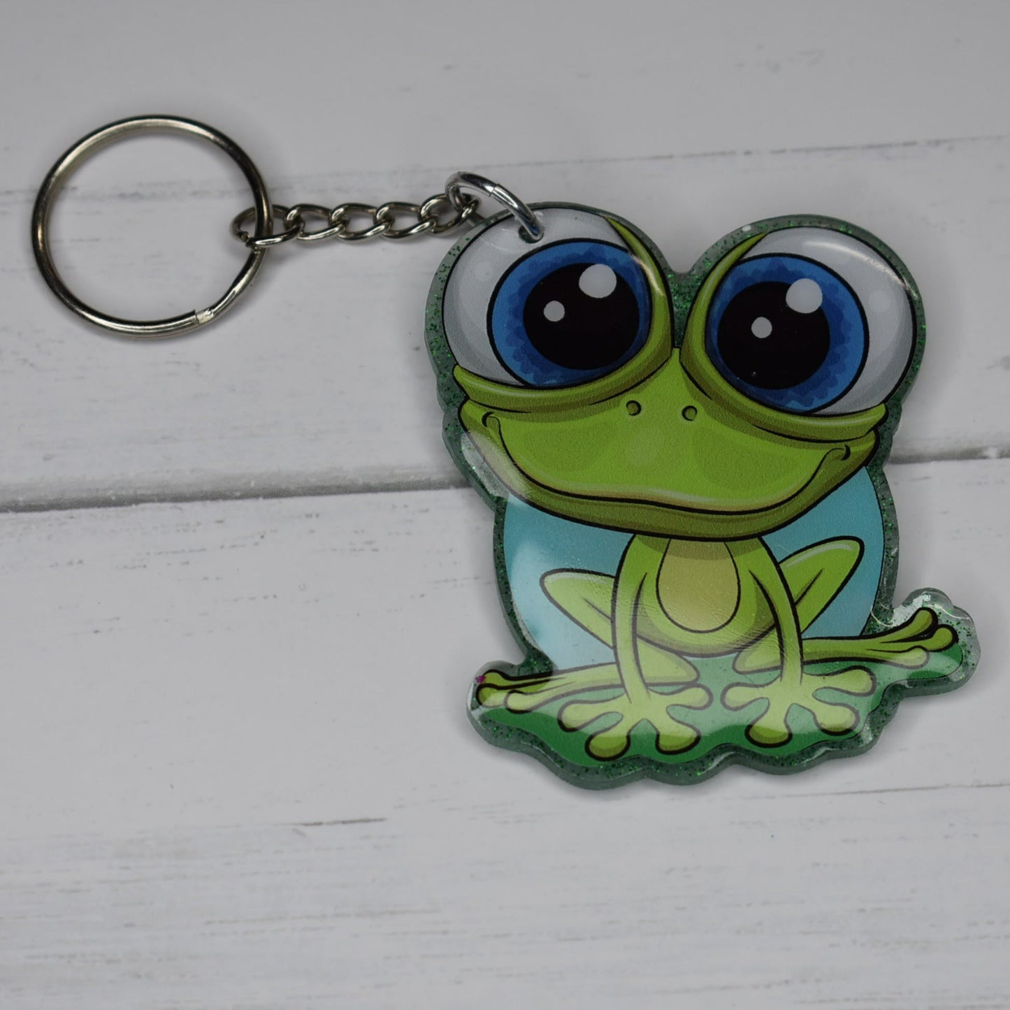 This Frog Keychain is hopping with happiness! Made from durable acrylic resin he comes with a green glitter background and a great happy smile. Available in 2 sizes. Small measures 1.5" x 2" and the large at 2" x 2.5".