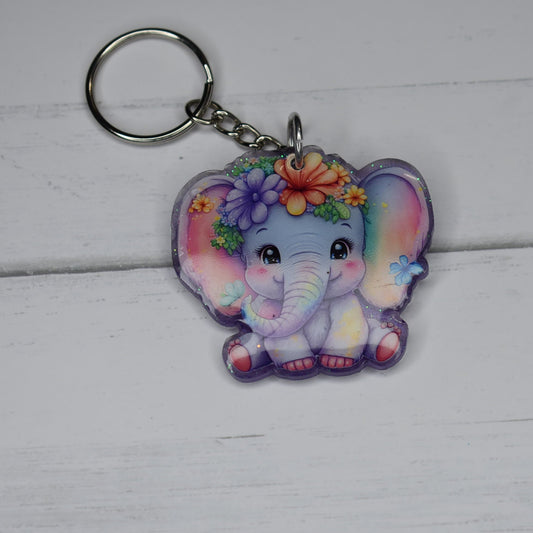 This Keychain features a charming Floral Elephant design. Made of durable acrylic resin, it boasts a sparkly lilac backing and a lovely elephant adorned with beautiful flowers. Expect it to brighten up anyone's day.