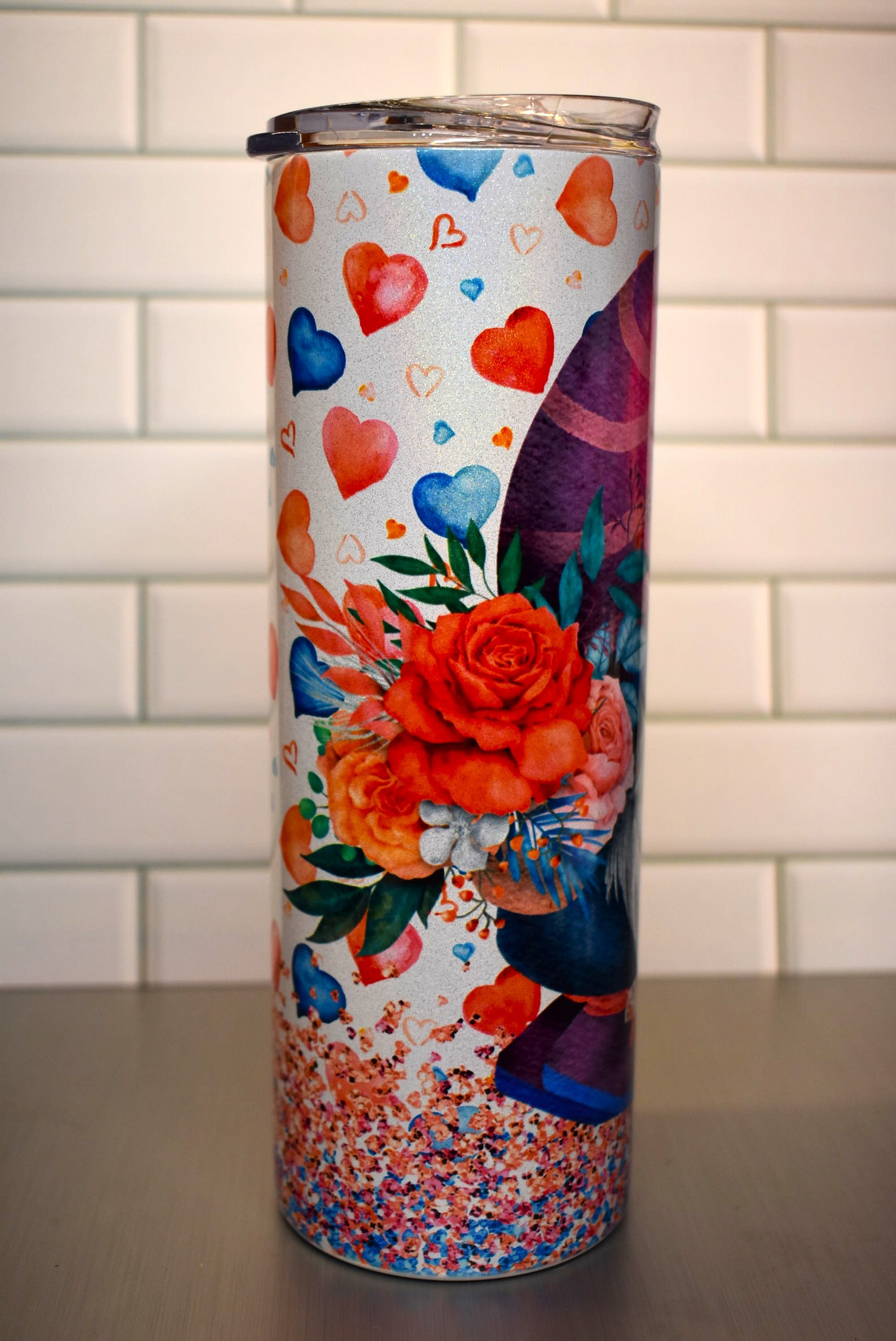 This 20 oz tumbler features a Gnome Love Couple Nose To Nose standing in confetti and floating hearts around them.