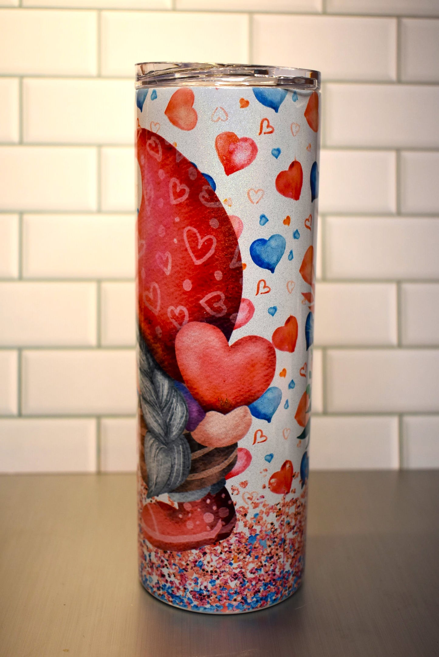 This 20 oz tumbler features a Gnome Love Couple Nose To Nose standing in confetti and floating hearts around them.