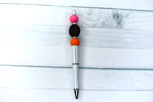 Coffee break. Silicone beaded pen here with a coffee bean focal bead with a pink & orange accent bead separated by sparkling gem rings. 1 extra black ink refill included