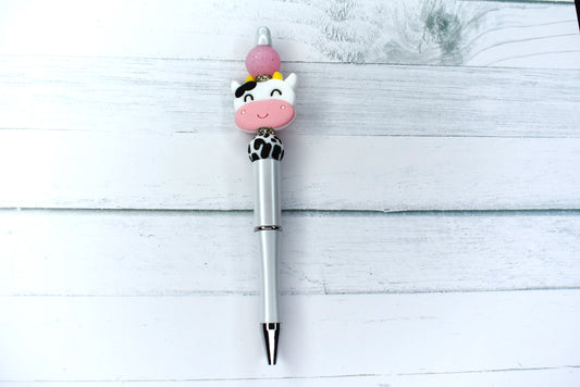 Another item from our cow collection. This silicone beaded pen pen has a white base, happy cow focal bead and surrounded with a cow pattern bead, pink glitter bead and 2 sparkling gem rings. 1 extra black refill included.