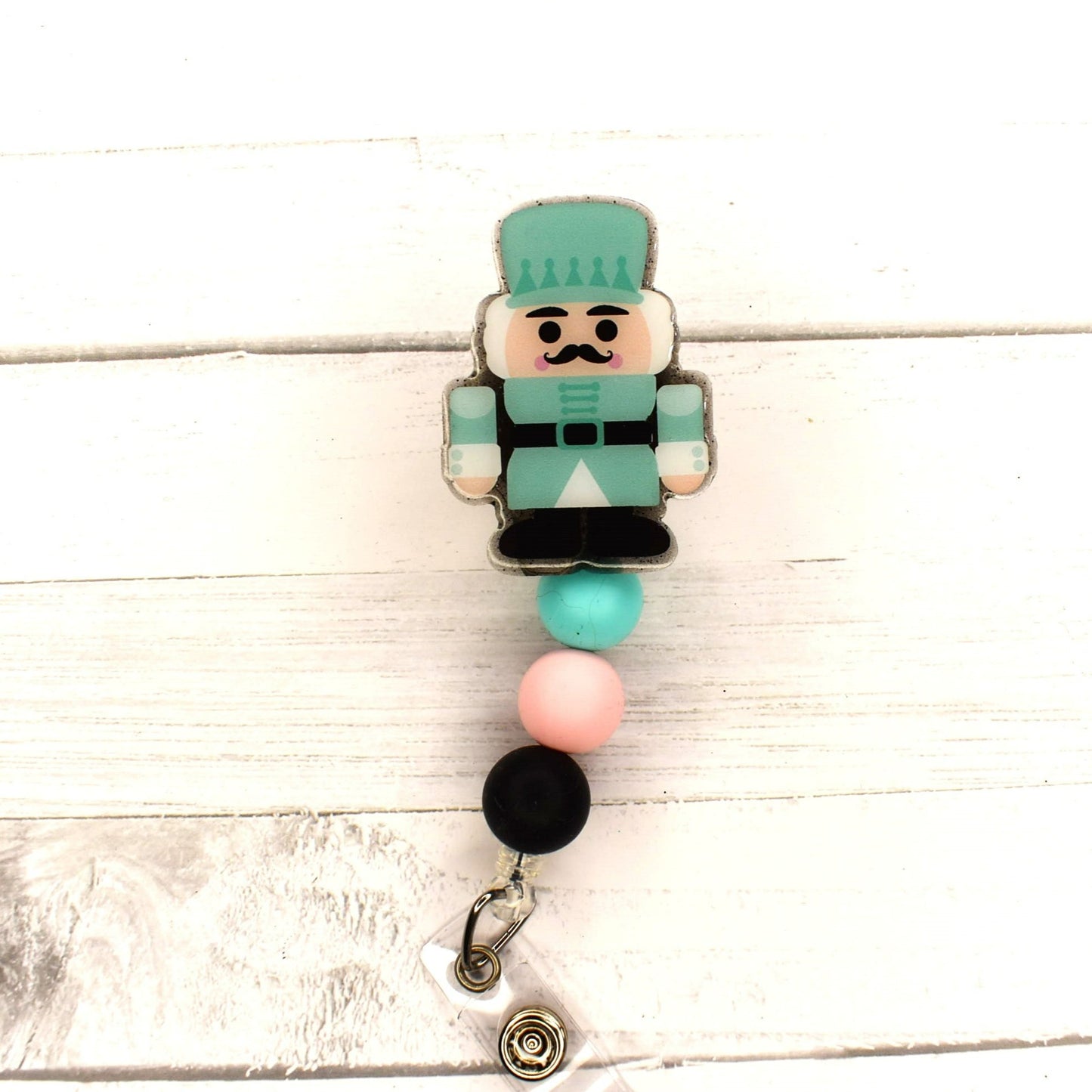 This acrylic Nutcracker in teal uniform badge reel features 2 different combinations of silicone bead accents, and is the perfect choice for Christmas festivities.