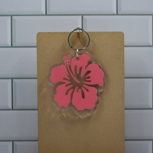 This acrylic keychain boasts a clear resin base with an eye-catching pink Hibiscus flower design.