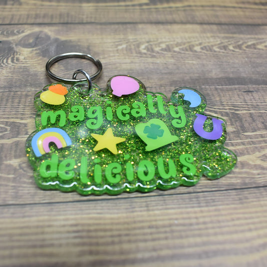 Acrylic keychain with a clear resin base mixed in with green glitter. Magically Delicious in green lettering and those fun shaped marshmallow treats... Just Add Milk!