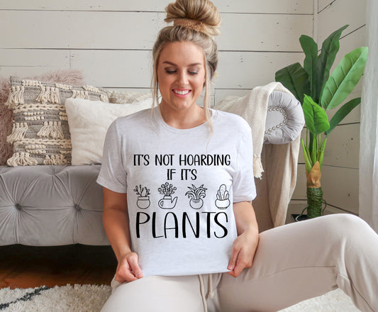 This Unisex adult T-shirt features a Screen Print Transfer of the phrase "It's Not Hoarding If It's Plants" in black lettering. It is crafted from 5.3 oz. of 100% preshrunk cotton